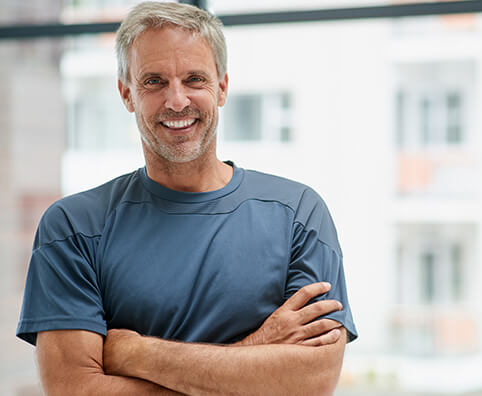 smiling man standing with his arms crossed